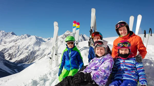 一群快乐的孩子们坐在雪地里 坐在滑雪的后面 山脉的最高峰微笑着 没有戴著五颜六色的面具 — 图库照片