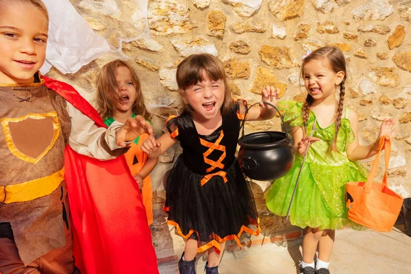 小さな子供たちの男の子と女の子のグループは ハロウィンの衣装 キャンディーバケツと石の壁の上のドレスに一緒に立っています — ストック写真