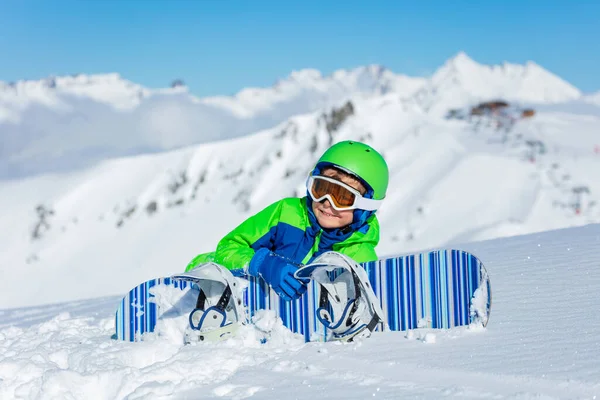 かわいい小さなスポーツ少年の肖像画は 日当たりの良いリゾート山の頂上に雪のように見えるスノーボードを保持しています — ストック写真