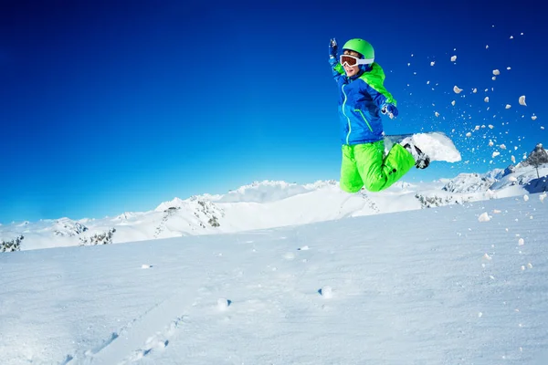 青空の上のスノーボードで幸せな男の子ジャンプし 空気中の雪の粉で手を持ち上げる山頂 — ストック写真