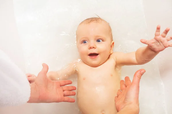 笑い赤ちゃんスプラッシュオンザバックでバスルームタブホームReatingのためにお母さんの手 ストック画像