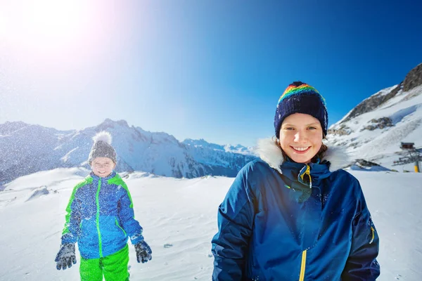 两个快乐的女孩和男孩一起站在一起 在美丽的山景上向空中扔雪 — 图库照片