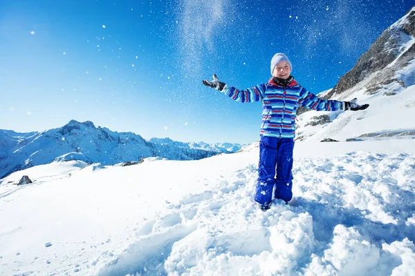可愛いです美しいです若いです女の子で鮮やかな青いスキー衣装雪を投げます空気中の山と空 — ストック写真