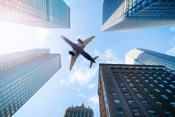 Beg commercial airplane over sky between skyscraper buildings in New York