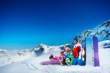 Bir grup mutlu genç yetişkin dağların tepelerinde kar tebessümleriyle kar altında yatıyordu.