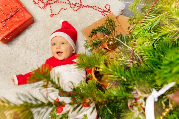快乐的小男孩躺在地毯上 张开嘴笑着看着装饰过的圣诞树 — 图库照片