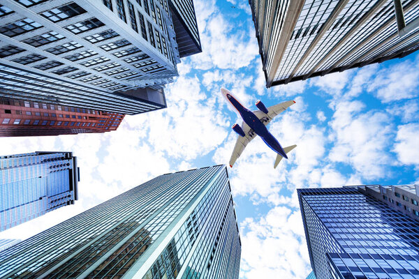 Airplane over sky between skyscraper buildings in New York