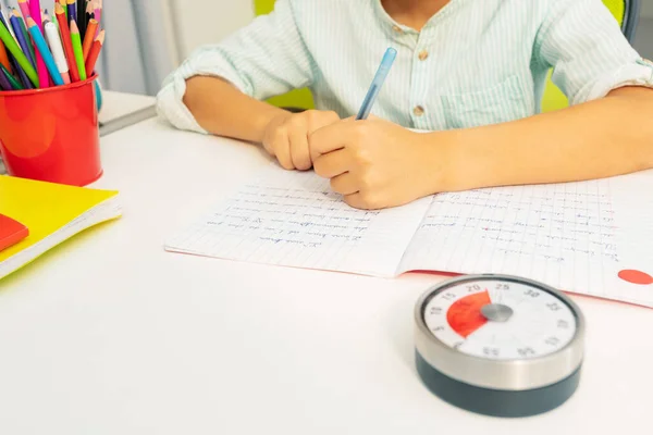 Mały Chłopiec Timerem Lekcji Podczas Pisania Ćwiczeń Tle — Zdjęcie stockowe