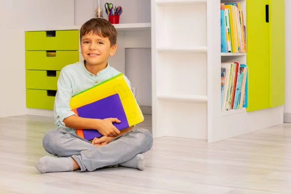 Gülümseyen Sakin Küçük Çocuk Elinde Kitaplarla Odasında Oturmuş Olumlu Bir — Stok fotoğraf