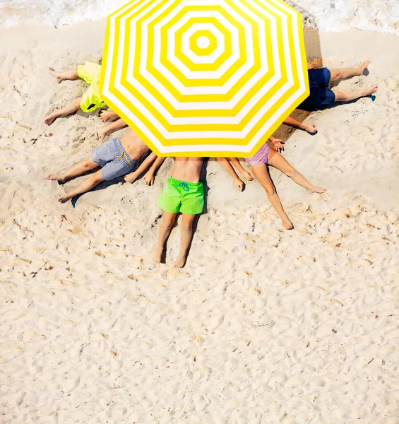 Gruppo Bambini Sdraiati Sulla Sabbia Della Spiaggia Sotto Grande Ombrellone — Foto Stock