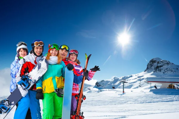 成群结队的年轻人坐在山顶上的雪板上 坐着滑雪车 — 图库照片