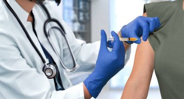 Hastane kliniğinde şırınga kullanarak hastanın kolunu enjekte eden doktor.