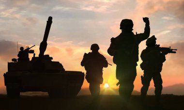 Askerler ve tanklar gün batımında savaş meydanında