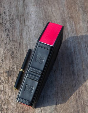 Tabut şeklinde kapaklı deri kitap. Kitap kapalı ve ahşap masa üzerinde duran frontal yakalanır