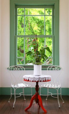 Pencere ve masa sandalyesi yeşil manzaralı odada.