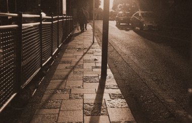 Yolun yüzeyi ve batan güneşin parladığı kaldırım.