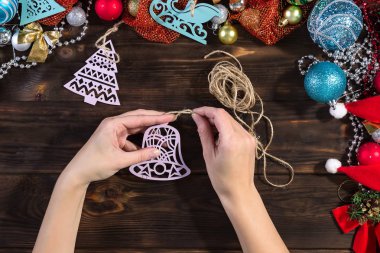 Koyu renkli ahşap bir masada Noel hediyeleri hazırlayan bir kız. Noel süslemeleri.