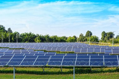 Mavi gökyüzü arkaplanındaki güneş paneli. Yeşil çimenler ve bulutlu gökyüzü. Alternatif enerji kavramı