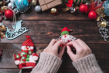 Koyu renkli ahşap bir masada Noel hediyeleri hazırlayan bir kız. Noel süslemeleri.