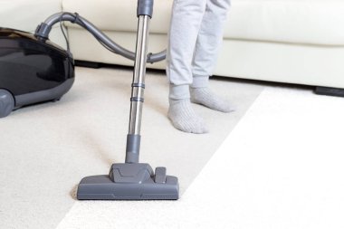 Oturma odasında elektrikli süpürge ile halı yıkama. Hafif renkli