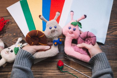 El yapımı hediyeler. El yapımı oyuncaklar. Tığ işi. Ahşap arka planda örme salyangozlar.