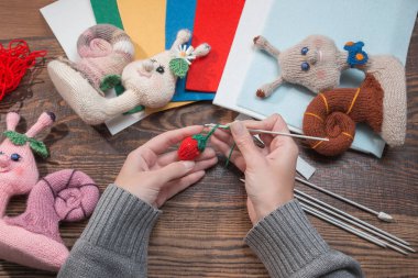 El yapımı hediyeler. El yapımı oyuncaklar. Tığ işi. Ahşap arka planda örme salyangozlar.