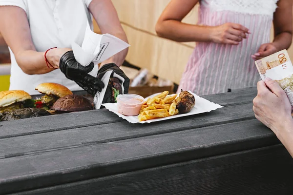 Chef making beef burgers outdoor on open kitchen food festival event. Street food ready to eat on a food stall.