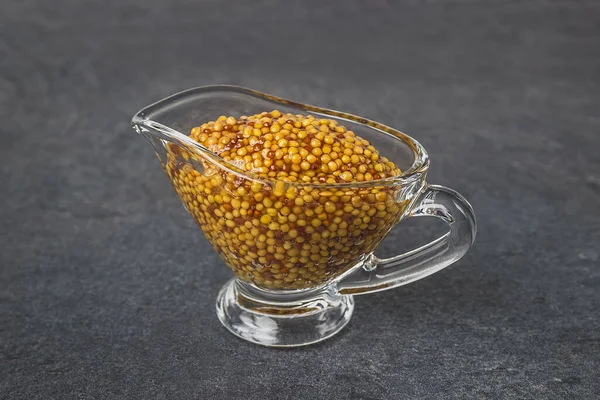 Moutarde française dans une saucière en verre sur fond noir. Moutarde de Dijon — Photo