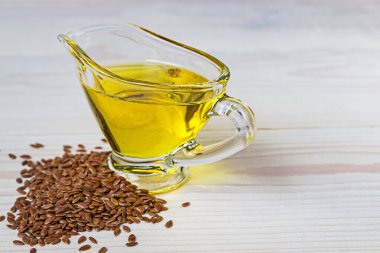 Cam sos kabında keten tohumu yağı. Beyaz arkaplanda keten tohumları