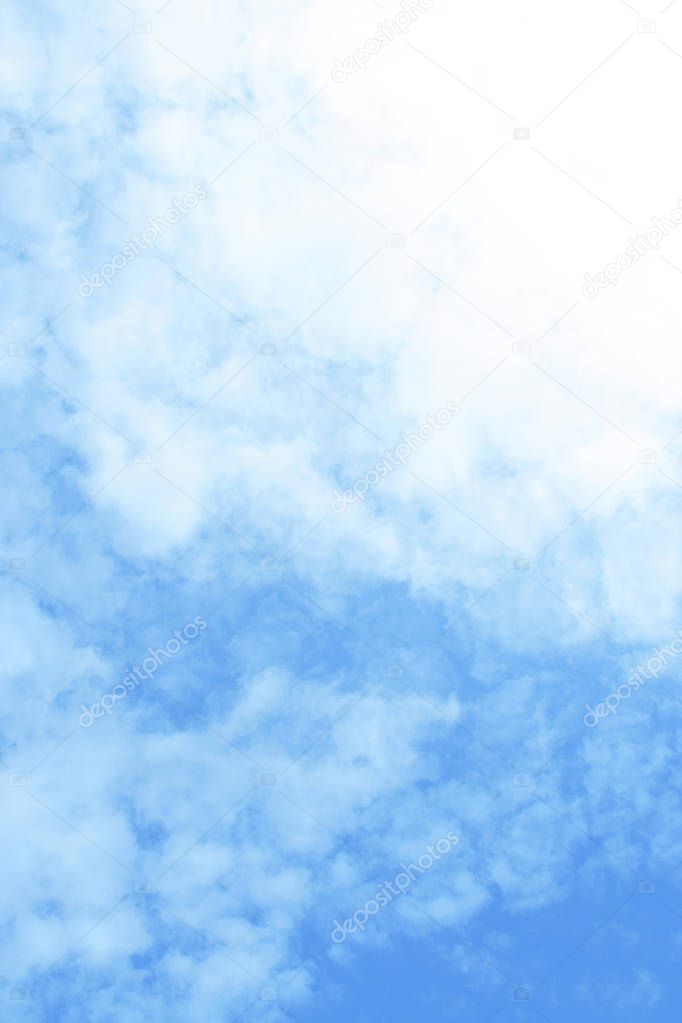 Summer cloudy background with copy space. Natural white clouds on blue sky. Vacation or travel background. Vertical.