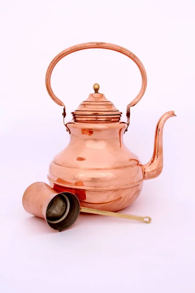An old copper kettle and a copper coffee jesse on soft background.coffee maker hanging on. Hanging retro design copper kitchenware set.