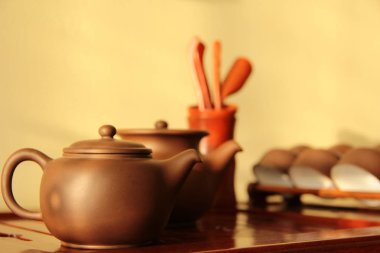 Çin yeşil çay bardağı hizmet çay bardakları bambu mutfak eşyaları ve ahşap lake ve öğütülmüş tepsi çay töreni kabartmalı yapısı ve gölgeleri ile bir duvara karşı altın ışık sarı ve kahverengi kapatın