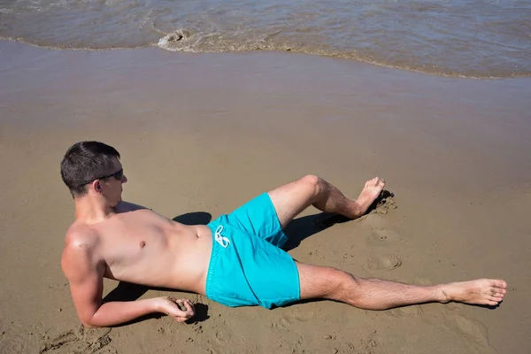 Brutala Ung Man Liggande Sanden Kanta Havet Stranden — Stockfoto