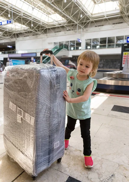 Маленькая девочка с большим чемоданом в аэропорту — стоковое фото