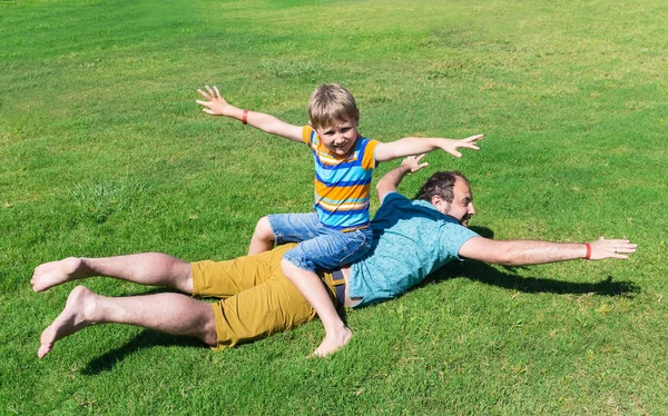 Dad and son rest on grass on sunny summer day — Stock Photo, Image