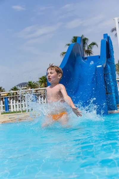 Little emotional boy in water park rides from slide — Stock Photo, Image