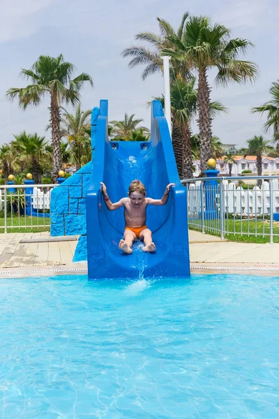 Menino no parque aquático cavalga de slide — Fotografia de Stock