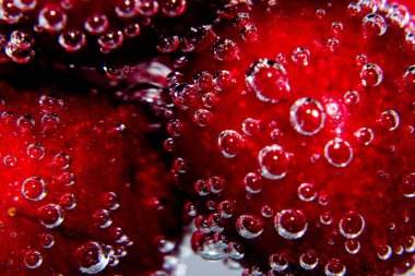 Beyaz şeffaf bir arka planda köpüklü soda içindeki kiraz.