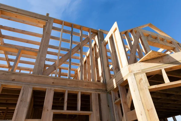 construction of a new frame house, where the frame itself is made of wooden logs and planks, closeup against a blue sky