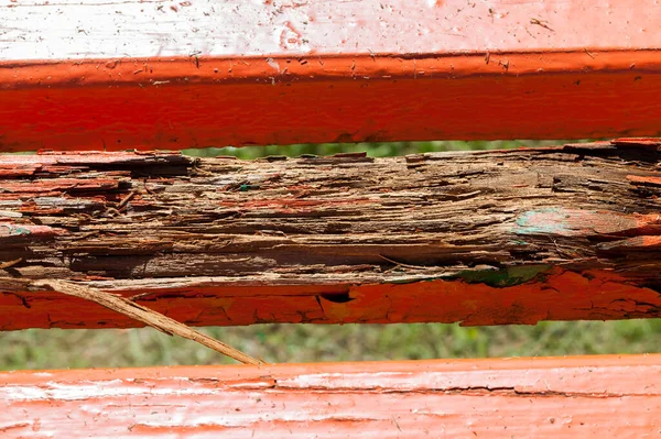 The old bench with a rotten part of the board is painted red
