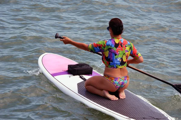 Attractive woman paddle boarder rowing her board on the Florida Intra-coastal Waterway in Miami Beach.