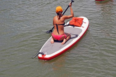 Çekici genç kadın diz çökmüş bir konumdan bir kürek tahta kürek.