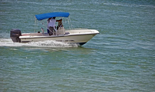 White motor with a blue nylon canopy powered by a single outboard engine.