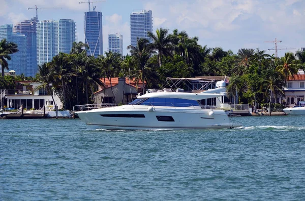 一个小型豪华机动游艇巡航由独家迈阿密海滩岛家园与迈阿密高层建筑在遥远的背景 — 图库照片