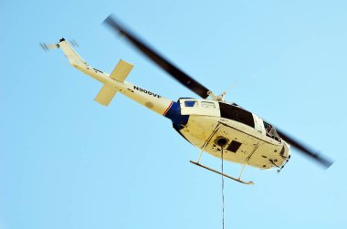 Hafif sanayi helikopteri çok katlı bir binanın çatısına ağır inşaat ekipmanları taşıyor. 