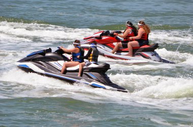 Four teenagers riding tandem on two jet skis on the Florida Intra-Coastal Waterway near Miami Beach clipart