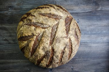 büyük tüm ev yapımı yuvarlak siyah ekmek üzerinde koyu ahşap masa ilginç doku yalanla