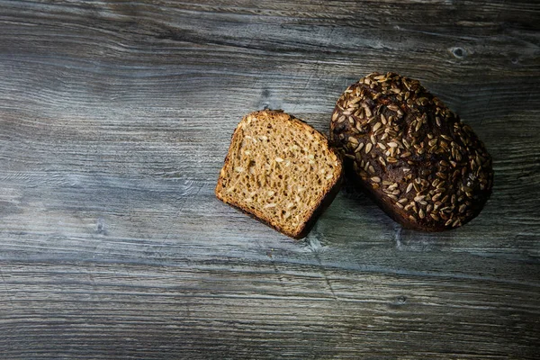 whole and half of delicious homemade rectangular rye bread with sunflower seeds on dark table background