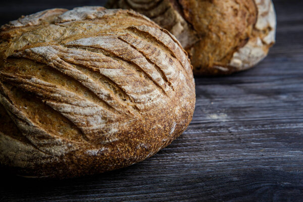 tasty whole homemade round white wheat bread lie on  dark wooden table