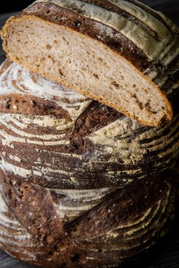 closeup iki büyük el yapımı yuvarlak siyah adet ekmek koyu ahşap masa üzerinde yalan